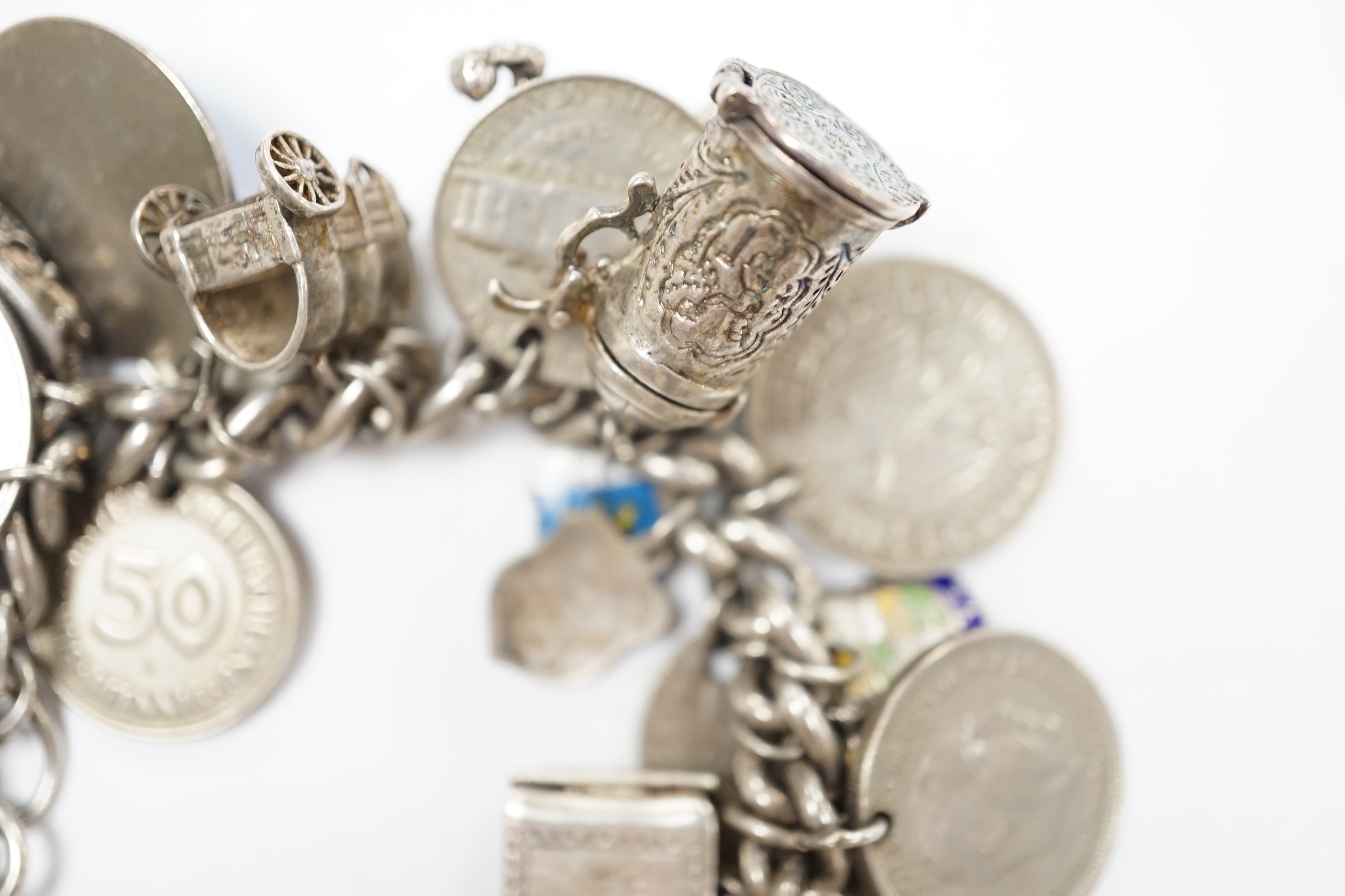 A silver charm bracelet, hung with assorted mainly white metal charms including tankard and Knight's helmet, two 'melted' ingots and a silver medallion.